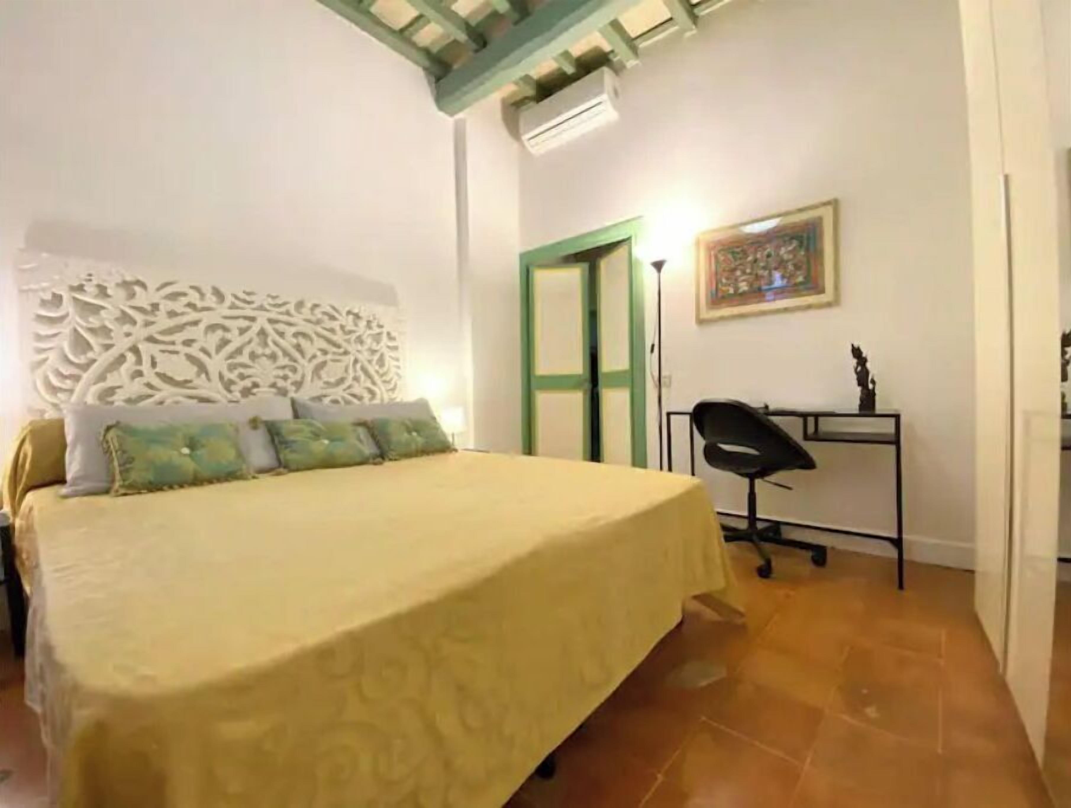 A bedroom with a bed, a desk, and a chair.