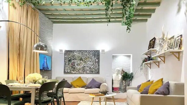 Un salon comprenant un coin repas, un ensemble de canapés, une table basse et un téléviseur.
