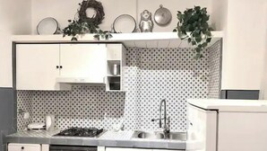 Une cuisine compacte avec des meubles blancs, un four encastré, une cuisinière à gaz et un évier.