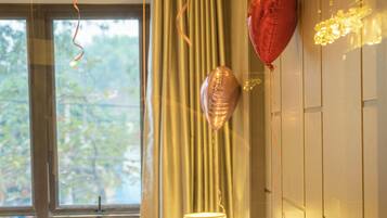 Une chambre d’hôtel avec un lit, des ballons et une fenêtre avec des rideaux.