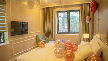 Une chambre d’hôtel avec un lit, des rideaux, une télévision et des ballons.