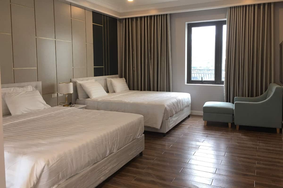 A hotel room with two beds, a seating area, and a window with curtains.