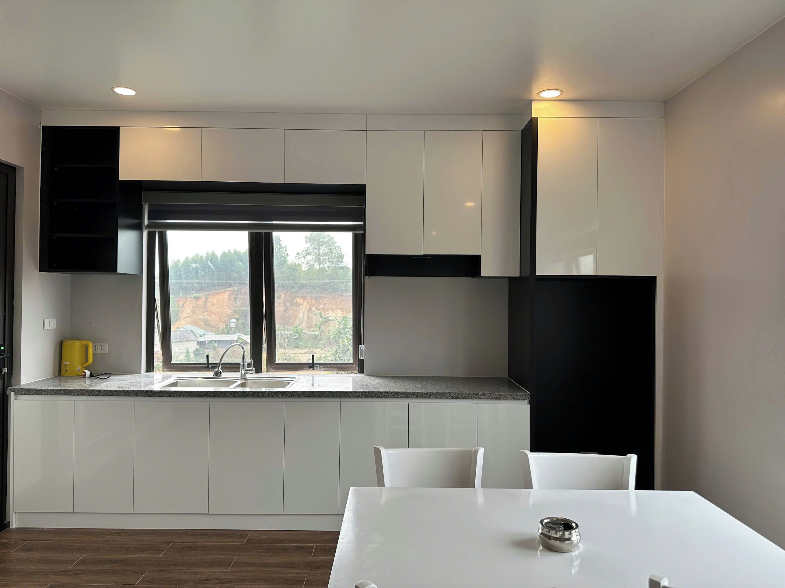 Eine moderne Küche mit weißen Schränken, einer Granit-Arbeitsplatte, einem Spülbecken und einem Essbereich mit weißem Tisch und Stühlen.