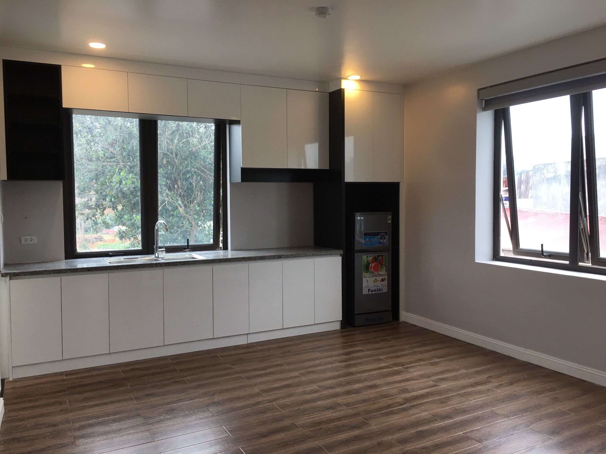 A modern kitchen with built-in cabinets, a built-in oven, and a window with a view of trees.