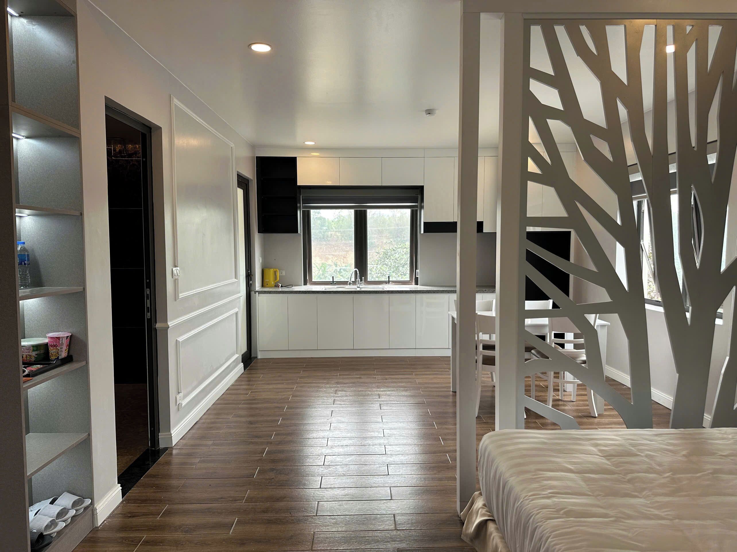 Une cuisine moderne avec des meubles blancs, une fenêtre et un plancher en bois.