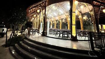 An outdoor dining area with a circular seating arrangement and a glass enclosure.