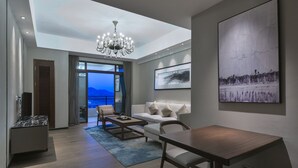 A modern living room with a sofa, coffee table, and a chandelier. There is a large window with a view of the city and mountains. - biguiyuan (Jiangmen)