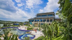 A hotel with a large pool, a covered outdoor area, and lush greenery. - biguiyuan (Jiangmen)