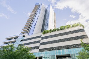 Stylish high-rise building with modern design, featuring large windows and lush greenery.
