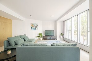 Relax in this stylish living room with a large L-shaped sofa, flat-screen TV, and a beautiful view of the outdoors.