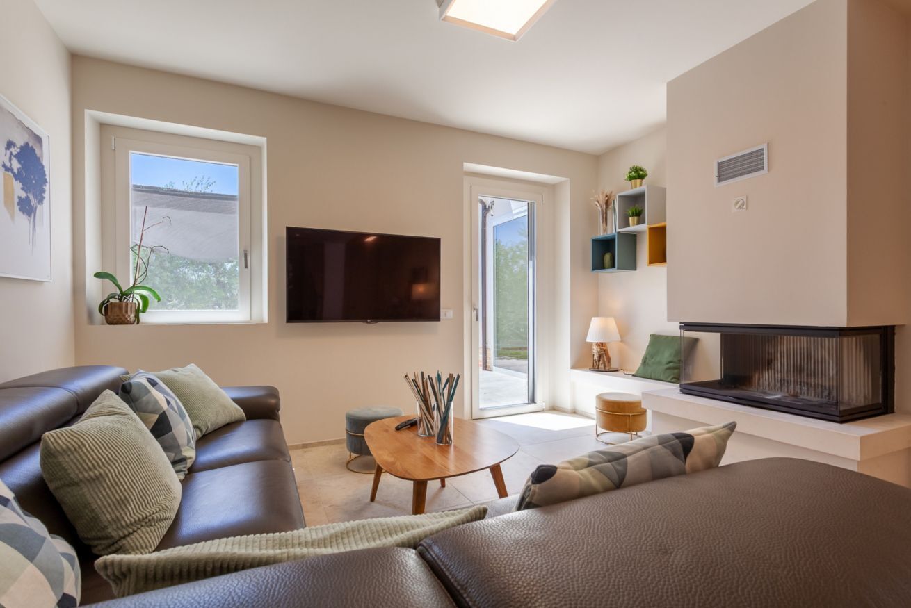 Ein modernes Wohnzimmer mit einer Couch, einem Couchtisch, einem Flachbildfernseher und einem Kamin.