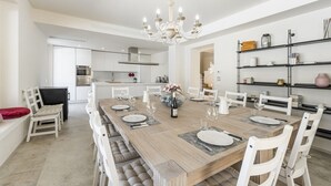 A modern dining area with a long wooden table set for six, surrounded by white chairs. - Villa Ada by MMega Villas  (Lapedona)