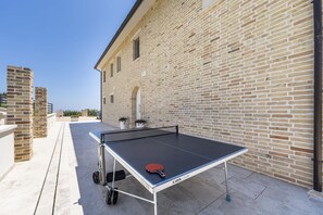 An outdoor ping pong table set up against a brick building with a clear sky. - Villa Ada by MMega Villas  (Lapedona)
