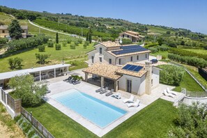 A villa with a swimming pool, solar panels, and a view of the surrounding countryside.