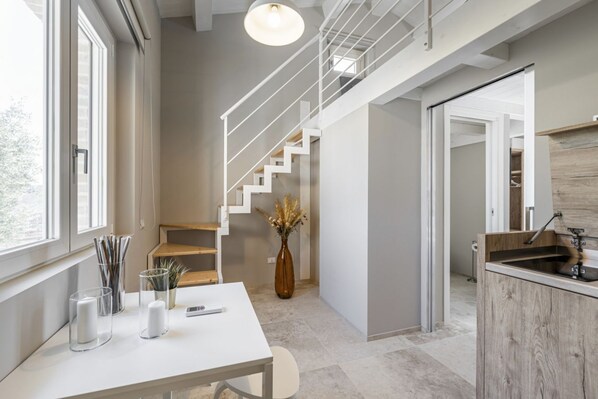 A modern interior with a staircase, a dining area with a table and chairs, and a kitchen area.