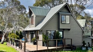 A two-story house with a gabled roof, a deck, and a fenced yard. - Maddison-Chalet (Dinner Plain)
