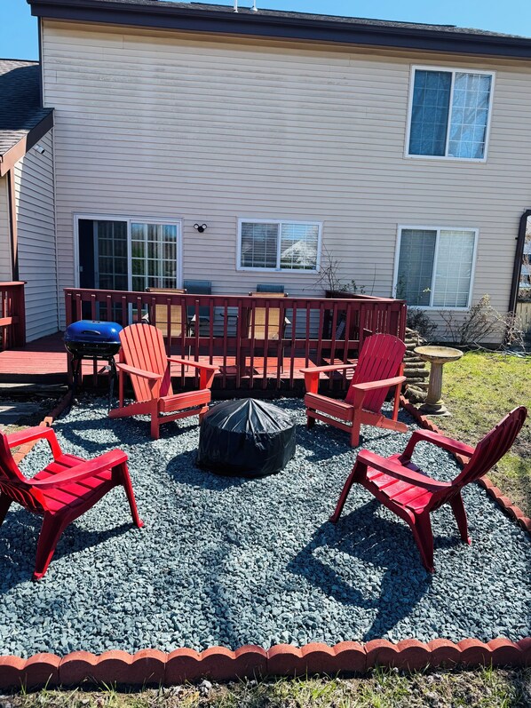 A covered patio area with red Adirondack chairs, a round table, and a barbecue grill. - Right in the center of everywhere in Dover (Dover)