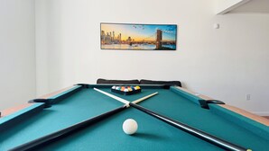 Une table de billard avec une peinture représentant un paysage urbain accrochée au-dessus.