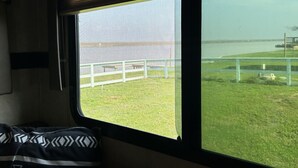 A window with a view of a grassy area and a fence. - This property has it all! Beach and Intercoastal frontage. (Bay City)