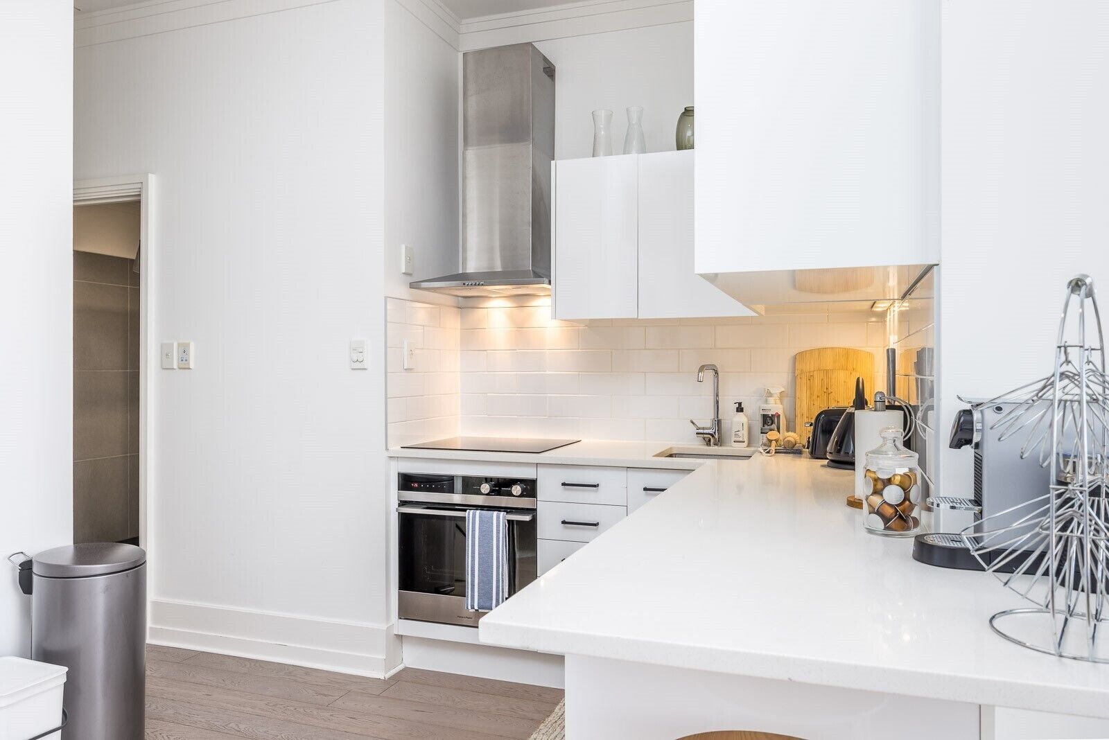 Une cuisine moderne avec des meubles blancs, des appareils en acier inoxydable et un design épuré et minimaliste.