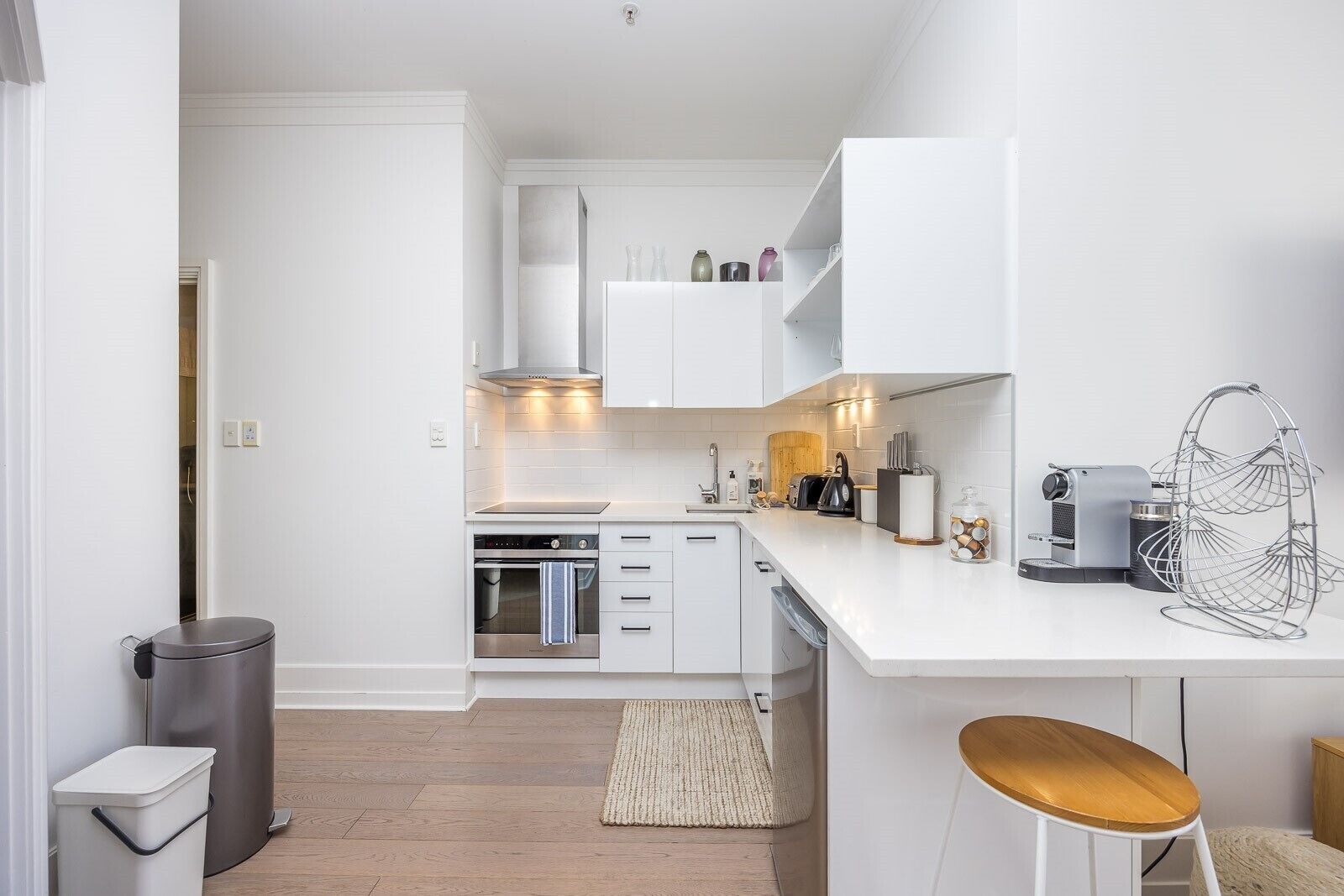 Eine moderne Küche mit weißen Schränken, einem eingebauten Backofen und einer Kaffeemaschine.