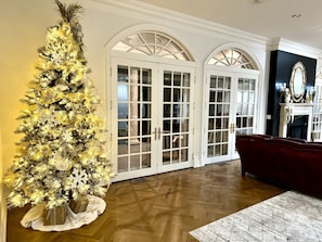 Ein geräumiges Wohnzimmer mit einem großen Weihnachtsbaum, Holzböden und einem roten Sofa.