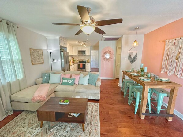 A living room with a sofa, coffee table, and a dining area with stools.