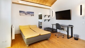 Une chambre à coucher moderne, équipée d’un lit, d’un bureau, d’une chaise et d’un téléviseur.