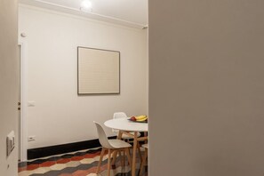 A dining area with a white table and chairs, a framed artwork on the wall, and a fruit bowl on the table. - La dolce vita is around the corner (Roma)