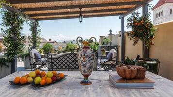 A terrace with a table set for dining, a decorative vase, and a view of the cityscape.