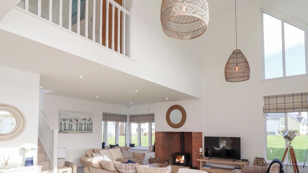 Un salón amplio con techo alto, chimenea, televisor y balcón.