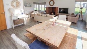 Un salón espacioso con una gran mesa de madera, sofás y una chimenea.