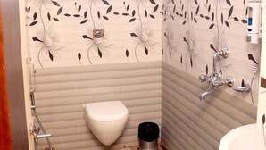 A bathroom with a toilet, shower, and sink. - Four Square Holidayz (Kanthi)