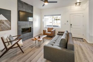 Un salon moderne avec une cheminée, un canapé, un fauteuil et une table basse.