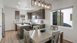 A modern kitchen with dark cabinets, a central island, and a dining area with four chairs.