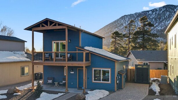 A two-story building with a balcony, a covered patio, and a view of mountains.