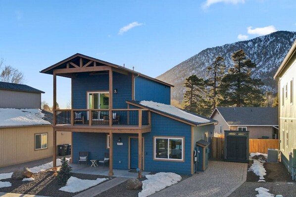A two-story building with a balcony, a covered patio, and a view of mountains.