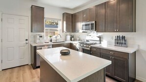 A modern kitchen with dark wood cabinets, a large island, stainless steel appliances, and a white countertop.
