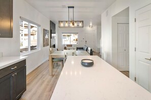 A modern kitchen with a central island, wooden cabinets, and a pendant light.