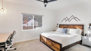 A bedroom with a bed, bedside tables, a desk, and a chair.