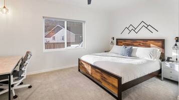 A bedroom with a bed, a desk, and a chair.