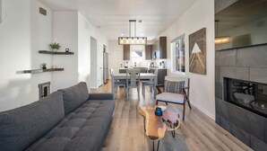 Un salon moderne avec un canapé gris, une table basse en bois et une cheminée.