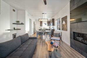 Ein modernes Wohnzimmer mit einem grauen Sofa, einem Holztisch und einem Kamin.