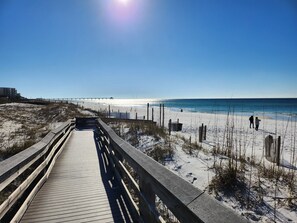 En träpromenad som leder till en strand med klar himmel.