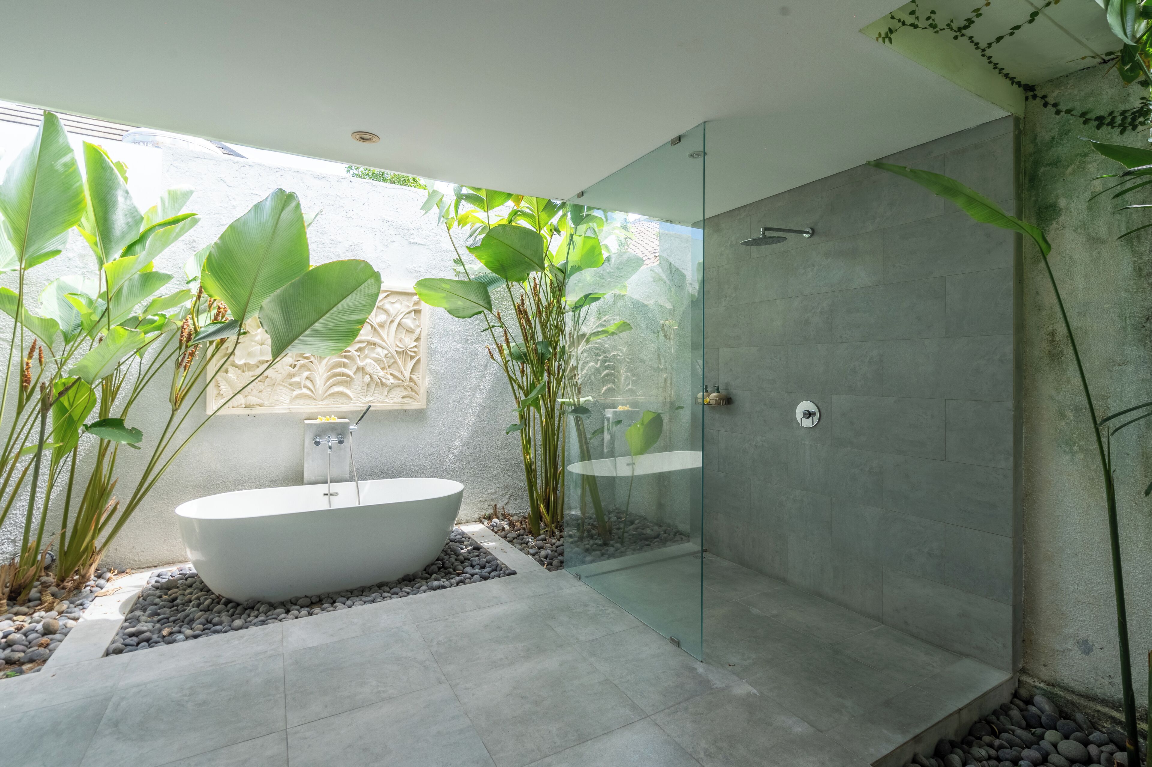 A modern bathroom with a freestanding bathtub, a glass-enclosed shower, and a decorative wall panel.