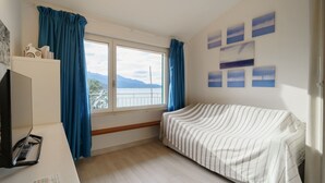 Une chambre avec un lit, un bureau, une fenêtre avec des rideaux et une vue sur les montagnes.