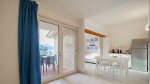 Un appartement moderne comprenant un coin repas, une cuisine et une porte-fenêtre coulissante donnant sur un balcon.