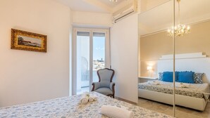 Une chambre à coucher avec un grand lit, une chaise, une fenêtre et un miroir qui reflète le lit.