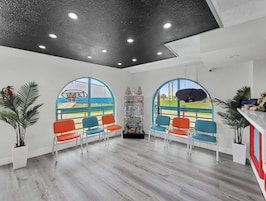 Un área de recepción con diseño moderno, que incluye un mostrador de recepción, zona de estar con sillas y vistas amplias a través de grandes ventanales.