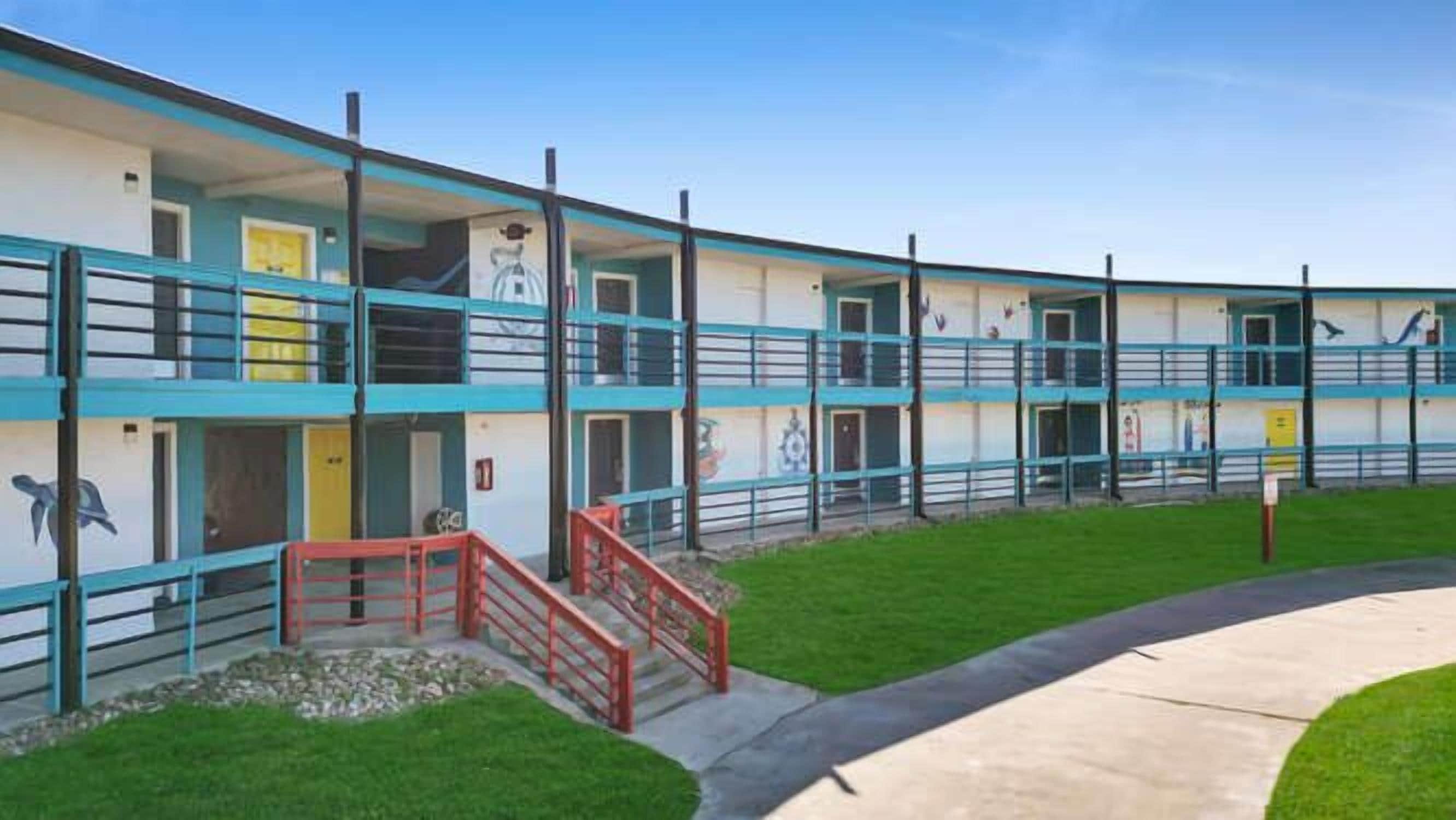 A motel with multiple floors, outdoor stairs, and a fenced area.